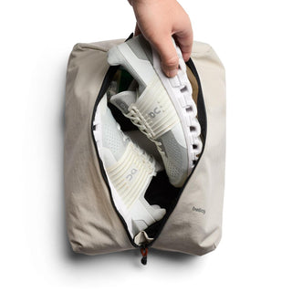 Bellroy Lite Packing Caddy 10L in beige holding white lightweight sneakers inside zippered compartment