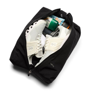 Bellroy Lite Packing Caddy 10L in black fabric holding white sneakers and travel essentials inside