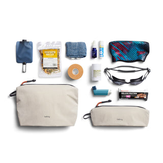 Bellroy Lite Pouch Duo in light beige recycled nylon with two sizes and black zipper pulls laid flat with travel essentials