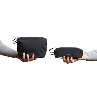 Hands holding black Bellroy Lite Pouch Duo made from recycled nylon with zipper closures