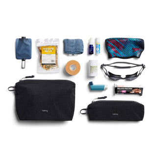 Bellroy Lite Pouch Duo showing black recycled nylon pouches with various daily essentials laid out nearby