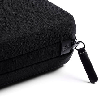 Bellroy Tech Kit close-up of textured black recycled fabric with zipper and logo tag on corner
