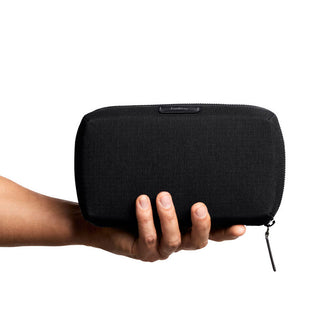 Bellroy Tech Kit held in hand showing black recycled fabric and compact zipper design