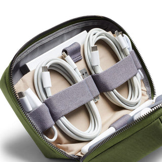 Bellroy Tech Kit organizing white charging cables inside green recycled fabric travel pouch