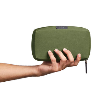 Hand holding olive green Bellroy Tech Kit with eco-friendly fabric and zipper detail against white background