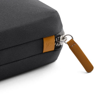 Bellroy Tech Kit close-up of black recycled fabric with tan leather zipper pull and logo patch