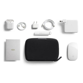 Bellroy Tech Kit Compact black recycled fabric case with organized white tech accessories laid out flat