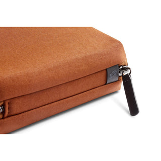 Bellroy Tech Kit Compact in rust orange fabric with black zipper pull and subtle logo tag close-up
