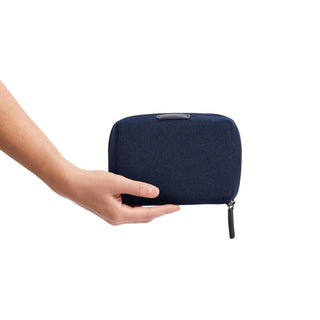 Hand holding navy blue Bellroy Tech Kit Compact made from recycled fabric with zip closure