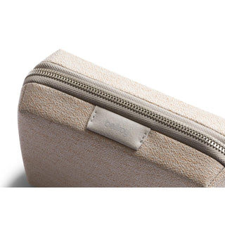 Bellroy Tech Kit Compact in beige textured recycled fabric with visible zipper and logo tab close-up