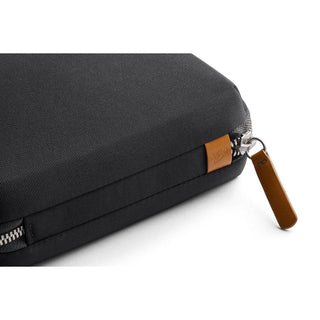 Bellroy Tech Kit Compact with textured black recycled fabric and brown leather zipper pull close-up view
