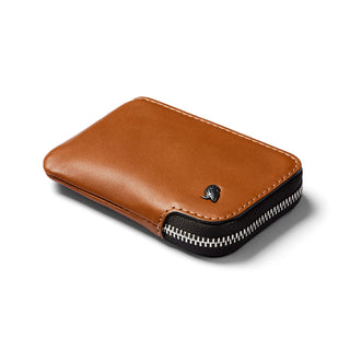 Bellroy Card Pocket in tan leather with metal logo and secure black zipper on white background