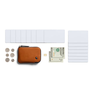 Bellroy Card Pocket in brown leather with zipper, displayed with coins, cash, and cards on white background