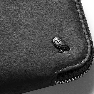 Bellroy Card Pocket close-up showing smooth black leather and embossed owl logo with zipper detail