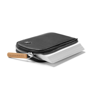 Bellroy Card Pocket in black leather with zipper and tan pull tab, fanned cards inside showing capacity.
