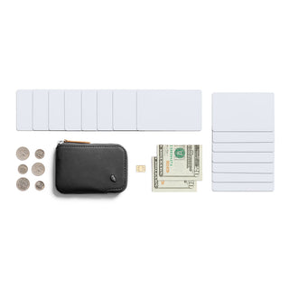 Bellroy Card Pocket black leather wallet with zipper, surrounded by cards, cash, coins, and a SIM card on white background