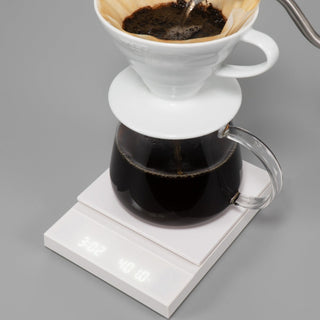 HARIO Polaris Coffee Scale in white with a glass carafe and drip coffee brewing setup on top