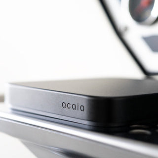 ACAIA Umbra Digital Scale in matte black with sleek compact design on reflective surface close-up angle