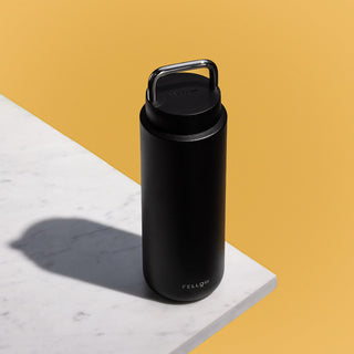 FELLOW black Fellow Carter Carry Tumbler (32oz/946ml) stainless steel with handle on white marble table