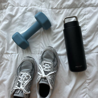 FELLOW Fellow Carter Carry Tumbler (32oz/946ml) black stainless steel with silver handle on white quilted surface