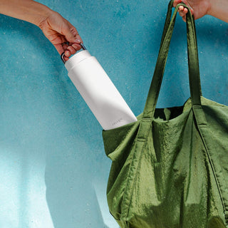 Fellow Carter Carry Tumbler (32oz/946ml) white stainless steel travel mug fitting into green tote bag