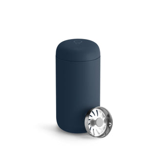 Fellow Carter Move Mug (12oz) in matte navy with stainless steel inner ceramic lid beside mug
