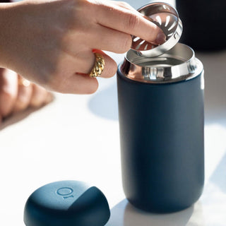 Fellow Carter Move Mug (12oz) in matte blue with stainless steel filter being inserted by hand