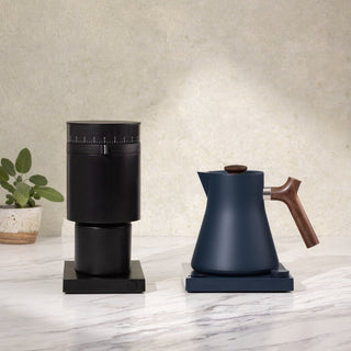 Fellow Corvo EKG Electric Kettle (120V) with wooden handle and navy matte finish on marble surface