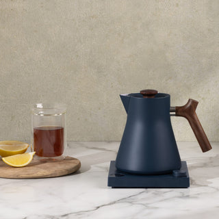 Fellow Corvo EKG Electric Kettle (120V) in matte navy with wooden handle on marble surface