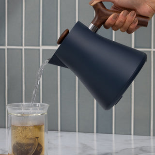 Fellow Corvo EKG Electric Kettle (120V) pouring water with wooden handle and matte black body