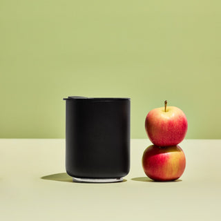 FELLOW Rocky Lowball Tumbler (10oz/296ml) matte black stainless steel with magnetic lid beside two apples