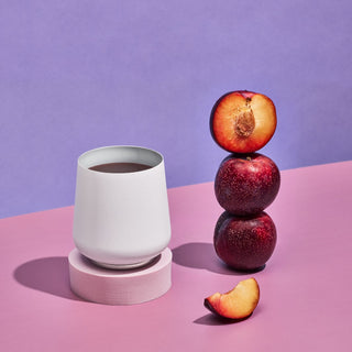 FELLOW Ruby Wine Tumbler (12oz/355ml) in white with stacked plums and plum slice on pastel background