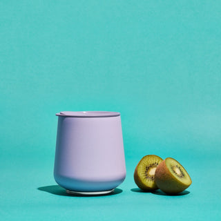 FELLOW Ruby Wine Tumbler (12oz/355ml) in matte lavender with smooth finish beside sliced kiwi fruit