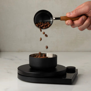 Fellow Tally Pro Precision Scale (Studio Edition) weighing coffee beans with a black stainless steel bowl and wooden scoop