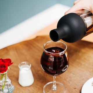 HARIO Filter In Coffee Bottle 650ml pouring cold brew coffee into a glass on wooden table