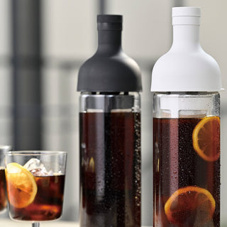 HARIO Filter In Coffee Bottle 650ml with black and white silicone lids filled with cold brew and lemon slices