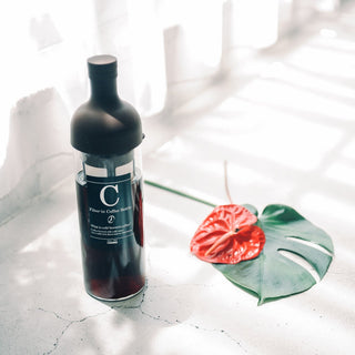 HARIO Filter In Coffee Bottle 650ml with black silicone cap and glass body in natural light