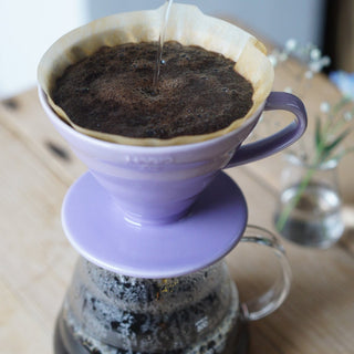 HARIO V60-02 Ceramic Dripper in lavender porcelain brewing coffee with paper filter and glass carafe beneath