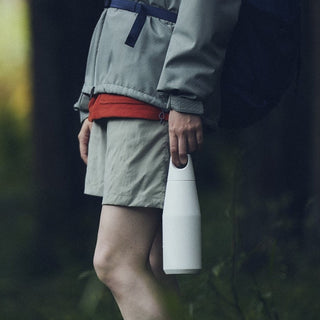 KINTO TRAIL Tumbler 580ml in white stainless steel held by a person wearing outdoor clothing