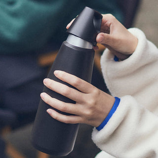 KINTO TRAIL Tumbler 580ml held in hands showing black powder-coated stainless steel and ergonomic lid design