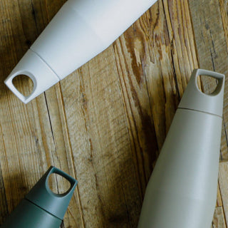 KINTO TRAIL Tumbler 1080ml in muted green, beige, and white stainless steel finish displayed on wood