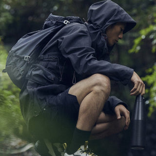 KINTO TRAIL Tumbler 1080ml held by hiker wearing black jacket and backpack in forest setting
