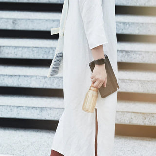 Person holding KINTO WATER Bottle 300ml in amber copolyester with silicone lid while walking outdoors