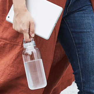 KINTO WATER Bottle 500ml held by hand showing clear copolyester body with silicone lid loop