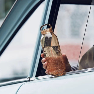 KINTO WATER Bottle 500ml held outside car window filled with sparkling water in amber copolyester design
