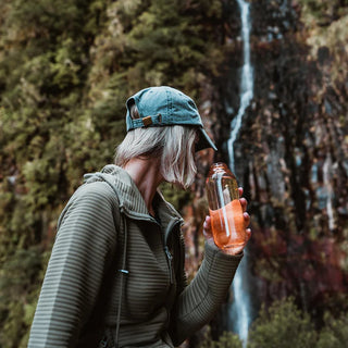 KINTO WATER Bottle 500ml held by person outdoors with clear amber copolyester body and silicone lid