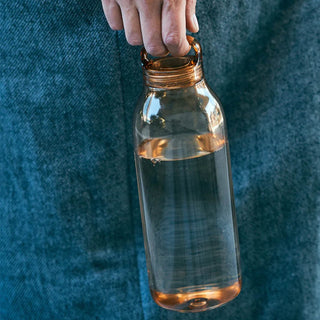 KINTO WATER Bottle 950ml held by hand with amber copolyester body and carrying loop on lid
