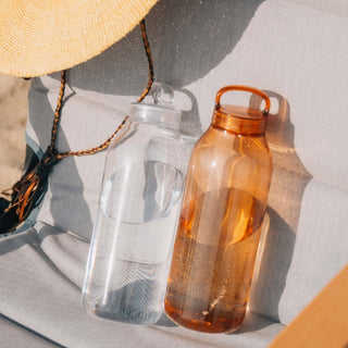 KINTO WATER Bottle 950ml in amber copolyester with handle and transparent clear version side by side on cushion