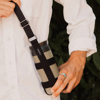 KINTO Travel Tumbler 500ml in beige stainless steel with black strap carried by hand outdoors