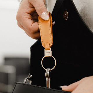 Orbitkey Loop Keychain in tan nappa leather held above a black handbag with metal keyring attached